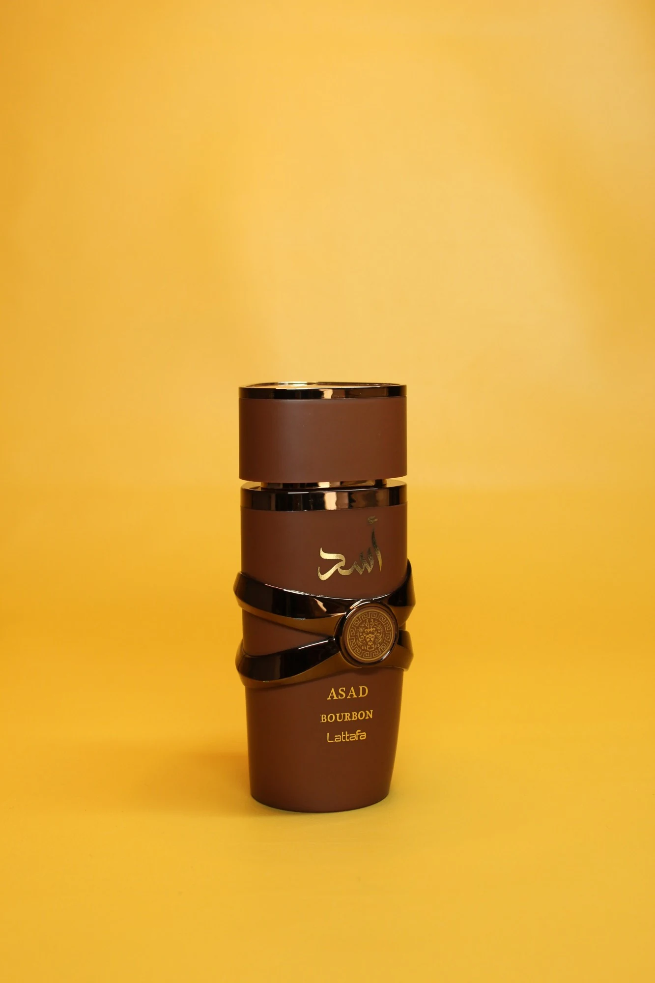 Asad Bourbon de Lattafa — frasco negro con banda dorada y medallón de león